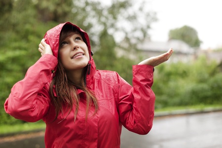 Beautiful woman in raincoat checking for rain