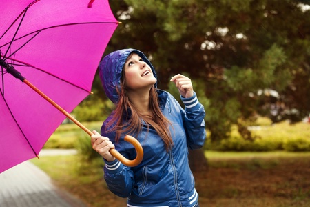 Beautiful woman with umbrella looking at the skyの写真素材