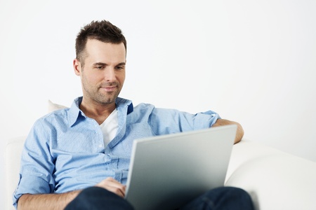 Attractive man using laptop on sofaの写真素材