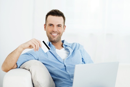 Handsome man holding credit card and using laptopの写真素材