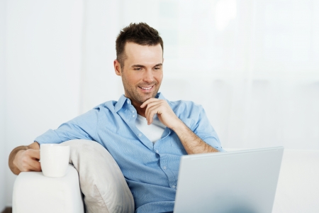 Thoughtful man with laptop and cup of coffeeの写真素材