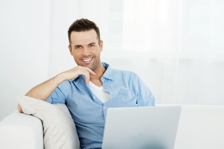 Portrait of handsome man with laptop on sofaの写真素材