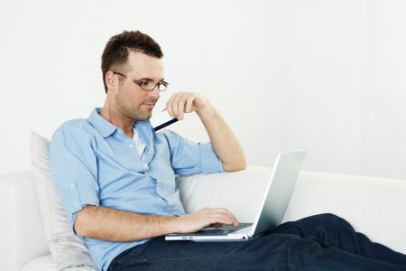 Man using credit card and laptop on couchの写真素材