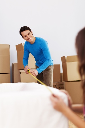Smiling couple measuring the sofa in their new homeの写真素材