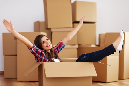 Cheerful woman sitting in a cardboard boxの写真素材