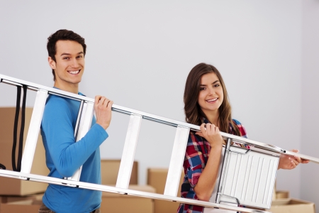 Young happy couple with a ladder during moving in new home の写真素材