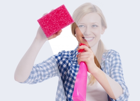 Young woman standing behind window and washing itの写真素材