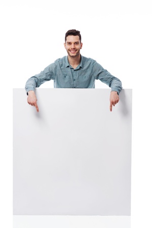Happy young man pointing at empty boardの写真素材