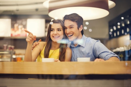 Happy young couple in cafe pointing to somethingの写真素材