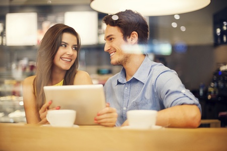 Flirting couple in cafe using digital tabletの写真素材