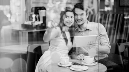 Happy couple in cafe holding digital tablet の写真素材