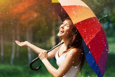 Laughing woman with umbrella checking for rain