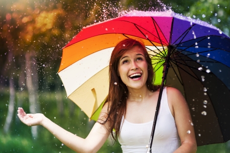 Surprised woman with umbrella during summer rainの写真素材