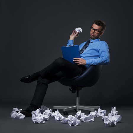 Sitting businessman throwing a crumpled paper with bad ideas on the floorの写真素材