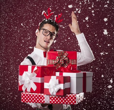 Grimacing man with stack of christmas presentsの写真素材