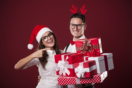 Smiling nerd couple showing christmas gift の写真素材