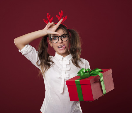 Nerdy woman with christmas gift showing loser signの写真素材