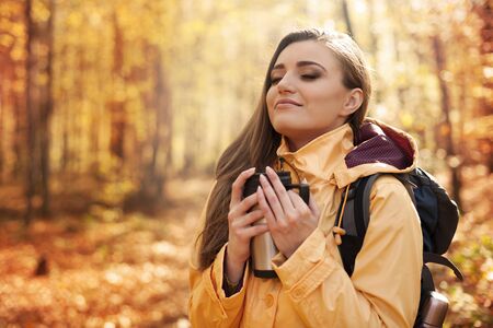 Smiling female hiker has a break for hot drink 