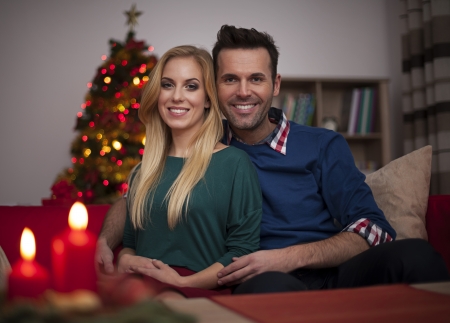 Loving couple sitting on sofa in living room during the christmas time の写真素材