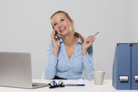 Happy woman gossiping on the phone in work の写真素材