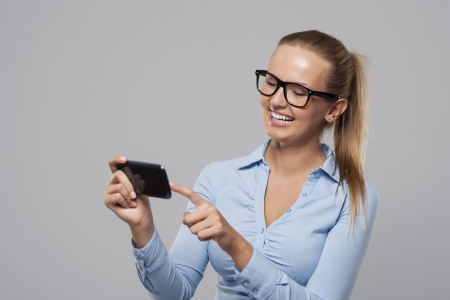 Smiling woman with glasses using mobile phone の写真素材