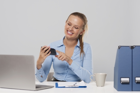 Happy woman using mobile phone during the office work 
の写真素材