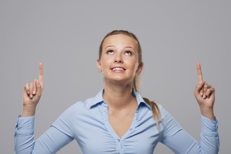 Blonde businesswoman pointing above at copy space の写真素材