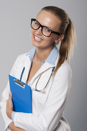 Smiling young female doctor with blue clipboardの写真素材