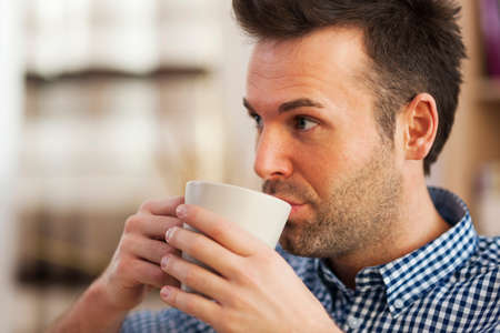 Close up man drinking coffee in homeの写真素材