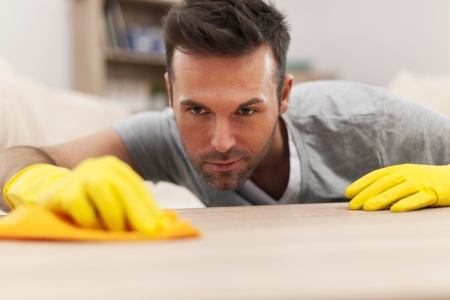 Handsome man cleaning stains off the tableの写真素材