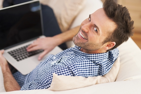 Smiling man using computer in living room の写真素材