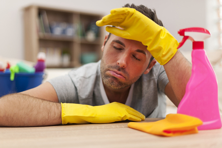 Tired man with cleaning equipmentの写真素材