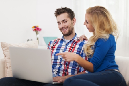 Happy couple using computer at home の写真素材