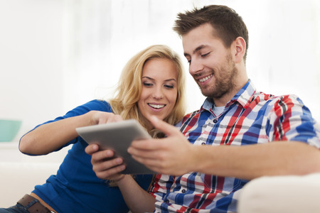 Smiling couple using digital tablet at home の写真素材