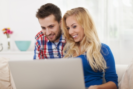 Smiling couple using laptop at home 
の写真素材