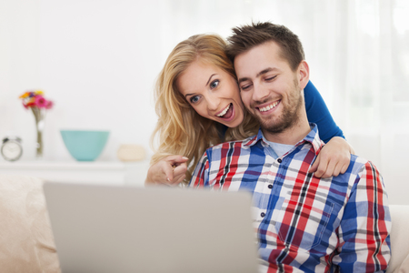 Surprised happy couple looking at laptop の写真素材