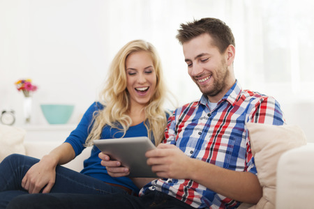 Happy couple using digital tablet at homeの写真素材