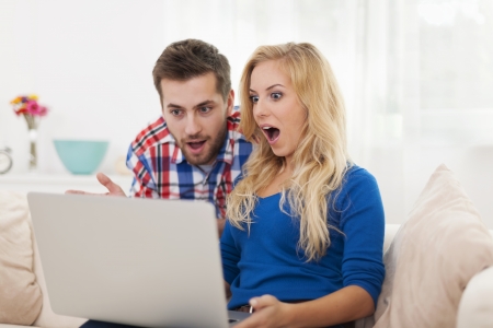 Shocked couple looking at contemporary laptopの写真素材