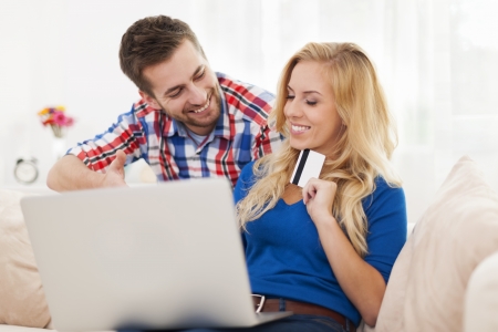 Portrait of couple with laptop and credit card in living room の写真素材