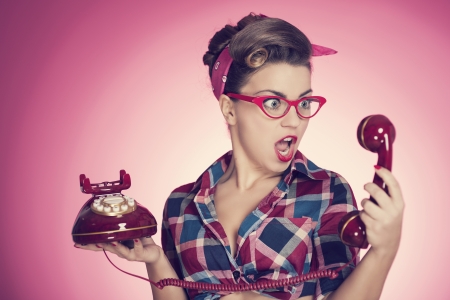 Shocked pin-up girl looking at retro telephoneの写真素材