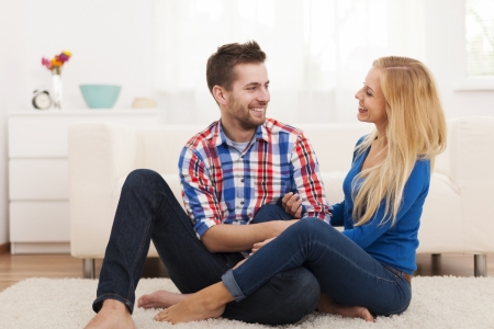 Loving couple sitting on floor in living room の写真素材