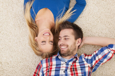 Cute young couple lying on carpet and look at each otherの写真素材