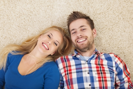Portrait of happy couple lying down on carpet の写真素材