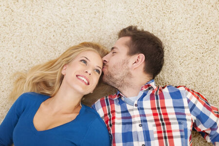 Kissing couple lying down on carpet の写真素材