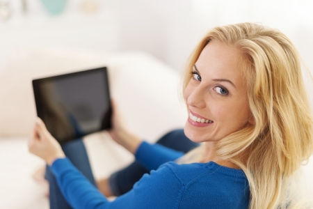 Beautiful young woman using digital tablet on sofa の写真素材