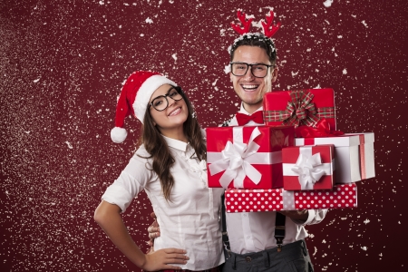 Smiling nerd couple with a lot of christmas presents during the snowing の写真素材