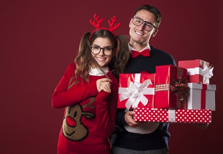 Smiling couple holding stack of christmas gifts の写真素材