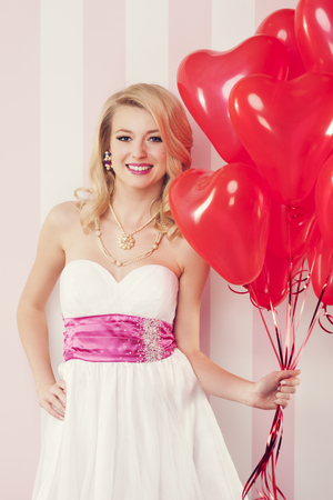 Smiling retro woman with red balloons in heart shape の写真素材