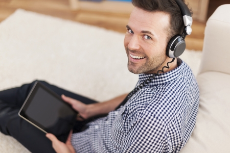 Portrait of smiling man listening music at home の写真素材