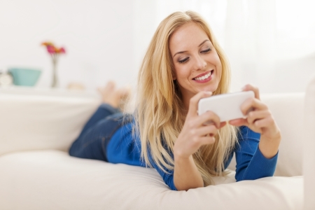 Woman relaxing on sofa with mobile phone の写真素材